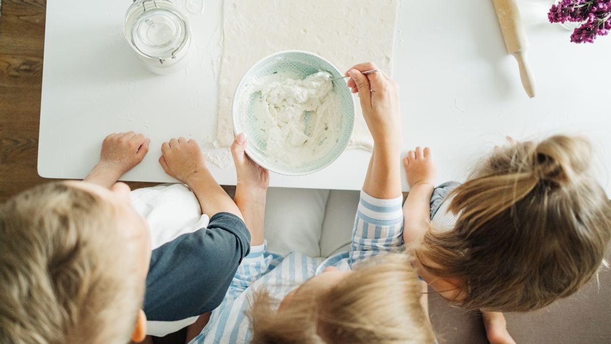 Three children mixing ingredients for homemade pastry in a bright kitchen setting.